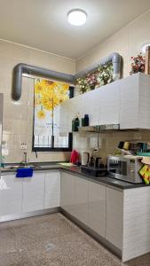 a kitchen with white cabinets and a window with flowers at 潔希民宿一館 in Hsin-chieh +16 photos