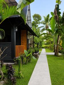 a walkway leading to a house with green grass at Tetebatu Valley Bungalows in Tetebatu
