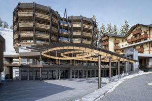 a large building with a curved roof in a parking lot at Campiglio PLAZA in Madonna di Campiglio
