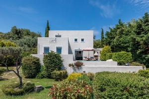 a white house with a garden and trees at Villa Calma in Patitiri