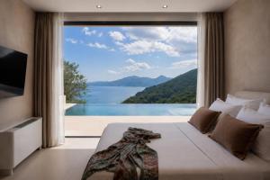 a bedroom with a large window with a view of a lake at Nomade Villas in Agios Ioannis Peristerion