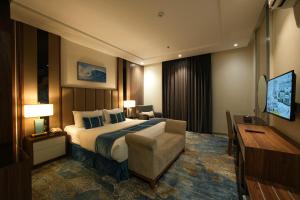 a hotel room with a bed and a couch and a television at جولدن بوجاري الضيافه in Khamis Mushayt