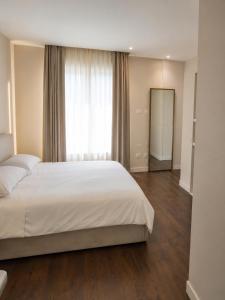 a bedroom with a white bed and a large window at Appartamento Doglio Lux in Cagliari
