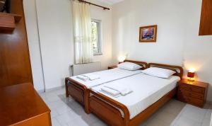 a bedroom with a bed with white sheets and a window at Ronzi Apartments in Kamena Vourla