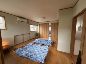 two beds in a large room with wooden floors at 雅ストリートハウス角館 in Senboku