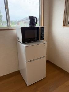 a microwave sitting on top of a white refrigerator at 雅ストリートハウス角館 in Senboku +1 photo