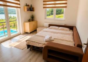 a bedroom with a large bed and two windows at LUX Villa Mavrovo in Mavrovo