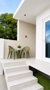 a white house with two green chairs and stairs at JRMN Property - 5 minutes from Blue Bay beach, Boka Sami & Kokomo Beach in Dorp Sint Michiel