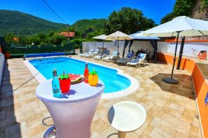 a pool with a table with drinks and fruit on it at Holiday Home Rocca with pool in Vrgorac