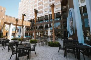 an empty courtyard with tables and chairs and palm trees at M Hotels at Porto Marina in El Alamein