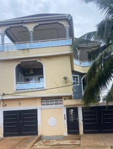 a large building with black doors and a palm tree at New ACROPOLE in Komé