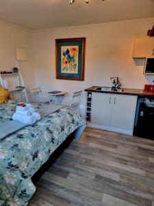 a bedroom with a bed and a kitchen with a sink at Sun Republik Studio in Whitianga