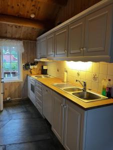 a kitchen with white cabinets and a sink and a window at Såmmårstuggu in Røros +18 photos