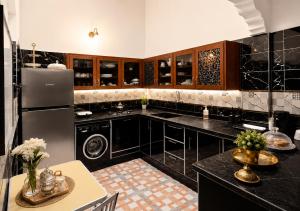 a kitchen with black counters and a refrigerator at Cozy Guesthouse in Aourir near Tamraght in Aourir