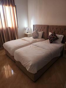 a bedroom with a large bed with white sheets and pillows at Appartement Aéroport Palm Marrakech-M9 in Marrakesh