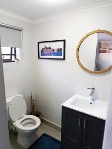 a bathroom with a toilet and a sink and a mirror at Reef View BnB in East London