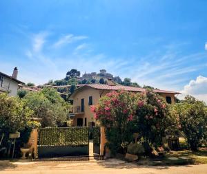 a house with a fence with a hill in the background at A casa di Lele a CAPALBIO in Capalbio
