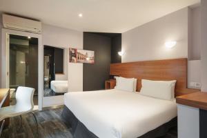 a bedroom with a large white bed and a desk at Exe Hotel El Magistral in Oviedo