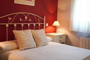 a bedroom with a white bed with a red wall at Villa Pereza in Socueva
