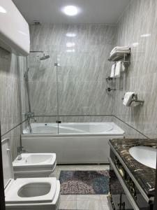a bathroom with two toilets and a tub and a sink at Sunrise Apartments in Dushanbe