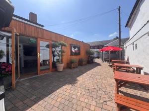 a patio with benches and tables in front of a building at Three Eagles Hotel&Restaurant and Garden Bar in Llangollen