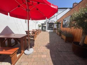a red umbrella on a patio with tables and benches at Three Eagles Hotel&Restaurant and Garden Bar in Llangollen