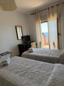 a hotel room with two beds and a window at Hotel Solemar in SantʼAlessio Siculo