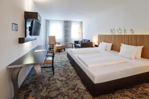 a hotel room with a bed and a desk at ARCOTEL Camino Stuttgart in Stuttgart