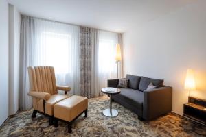 a living room with a couch and a chair at ARCOTEL Camino Stuttgart in Stuttgart +56 photos