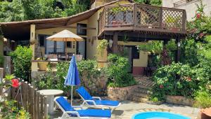 a house with a patio with chairs and an umbrella at Casa Serena in Pipa