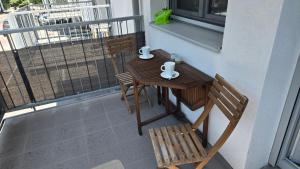 a table and two chairs on a balcony with a table and a window at Appartement LUFT bei Wien in Klosterneuburg