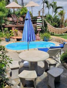 a table with an umbrella next to a pool at Casa Serena in Pipa