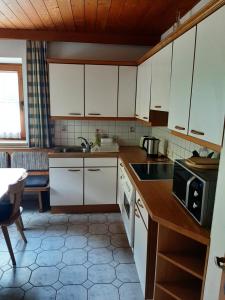 a kitchen with white cabinets and a sink and a microwave at Alpine cottage with exceptional view in Mayrhofen