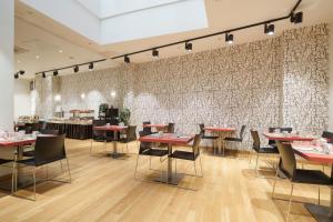 a restaurant with red tables and chairs in front of a wall at Exe Hotel El Magistral in Oviedo