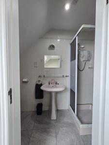 a white bathroom with a sink and a shower at Cope House Rooms in Killybegs