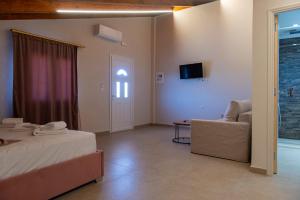 a bedroom with a bed and a couch and a tv at PERDIKA's HORIZON in Perdika