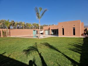 a house with a palm tree in front of a yard at Agadir sans vis a vis in Bouria