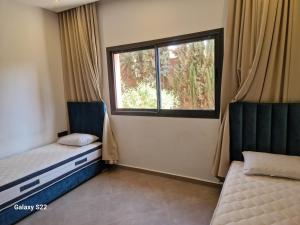 a bedroom with two beds and a window at Agadir sans vis a vis in Bouria +8 photos
