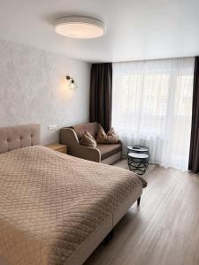 a bedroom with a bed and a couch at Taikos apartamentas in Mažeikiai