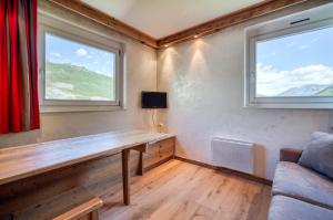 a living room with a table and two windows at Appartement Tommeuse 93 in Tignes