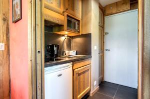 a small kitchen with wooden cabinets and a sink at Appartement Tommeuse 93 in Tignes +2 photos
