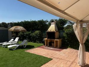 a grill in a yard with chairs and an umbrella at Casa Rural El Olivo in Segovia