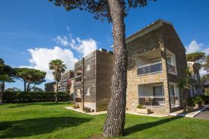 an exterior view of a house with a tree at Hôtel La Lagune in Lucciana