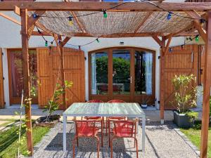 a patio with a table and chairs under a pergola at L'Aparté Nature, entre campagne et montagne in Jarrie