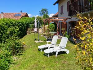 two white chairs and an umbrella in a yard at L'Aparté Nature, entre campagne et montagne in Jarrie