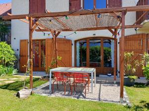 a table and chairs under a pergola in a yard at L'Aparté Nature, entre campagne et montagne in Jarrie