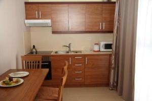 a kitchen with wooden cabinets and a table with a plate of food at Hotel Aquapark Žusterna in Koper