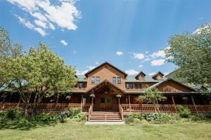 a large wooden house with trees in front of it at Chico Hot Springs Resort in White City