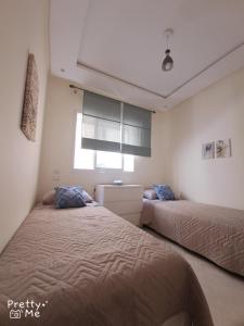 a bedroom with two beds and a window at Chaleureux appartement in Bouznika