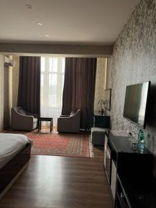 a hotel room with a bed and a flat screen tv at Sunrise Apartments in Dushanbe